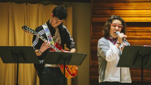 two students performing music on stage